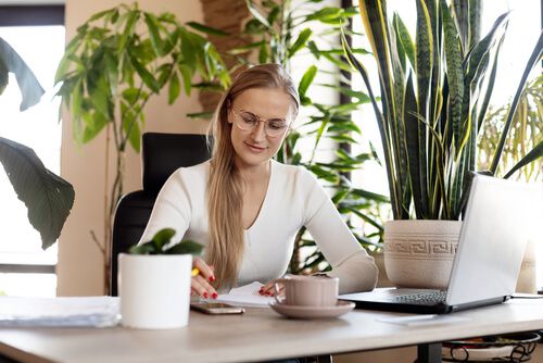 אישה עובדת לאחר שדאגה לעיצוב חדר עבודה ביתי